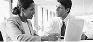 Photo of man and woman discussing what is displayed on laptop